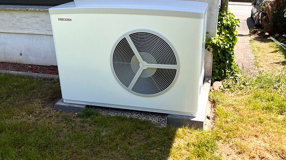 Luft-Wasser-Wärmepumpe als Außeneinheit neben einem Wohnhaus