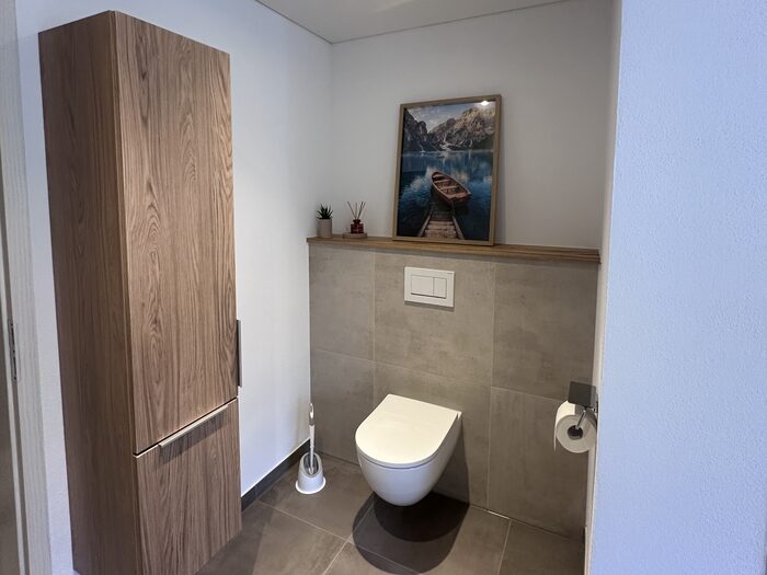 Gäste-WC mit wandhängendem WC und Hochschrank in Holzoptik